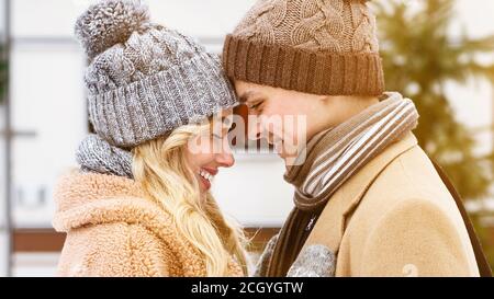 Romantisches junges Paar in gestrickten Hüten berühren Stirn im Winter Datum im Freien Stockfoto