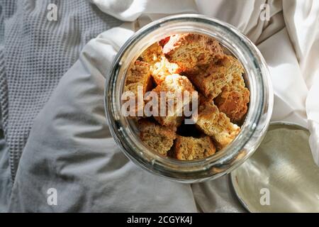 Frisch gebackener Zwieback in einem Glasbehälter auf Bettwäsche und weißer Bettwäsche. Stockfoto