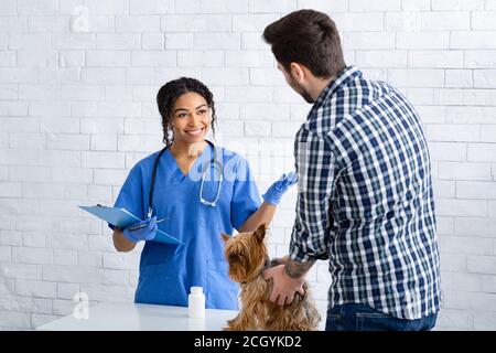 Glücklich Tier Arzt im Gespräch mit männlichen Kunden mit niedlichen kleinen doggy in der Tierklinik Stockfoto
