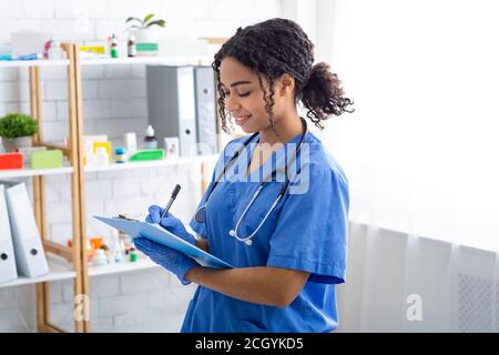 Glücklicher Tierarzt schreibt auf Clipboard in der Tierklinik Stockfoto