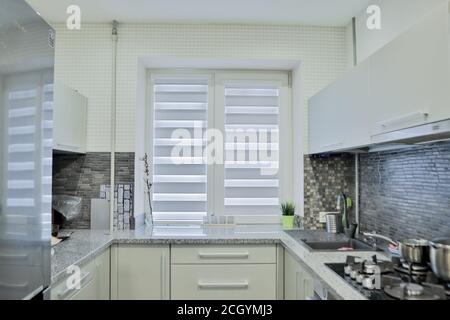 Moderne graue Küche verfügt über graue flache Front Schränke gepaart mit grauen Arbeitsplatten und einem glänzenden grauen linearen Fliesen backsplash. Stockfoto