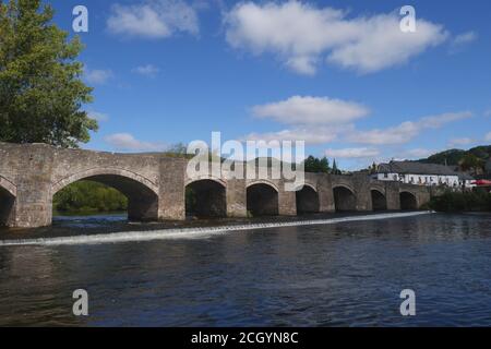 Die denkmalgeschützte Brücke des 18. Jahrhunderts, die über einem Wehr, über dem Fluss Usk, Crickhowell, Powys, Wales, Vereinigtes Königreich, steht Stockfoto