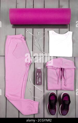 Overhead-Ansicht Womans Workout-Outfit, Weibliche Sportausrüstung, rosa Sport auf grauem Holzhintergrund, Draufsicht, flach liegend Stockfoto