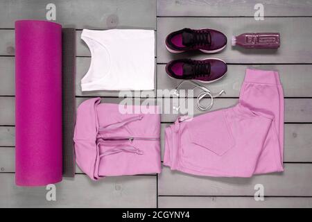 Overhead-Ansicht Womans Workout-Outfit, Weibliche Sportausrüstung, rosa Sport auf grauem Holzhintergrund, Draufsicht, flach liegend Stockfoto