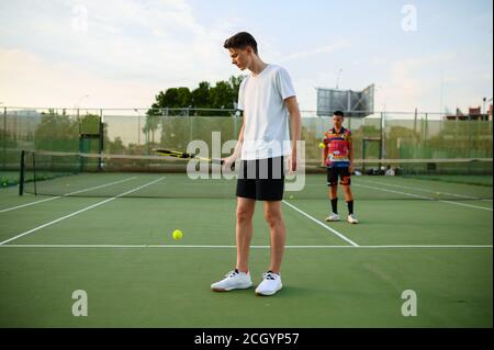 Männliche Tennisspieler mit Schlägern treffen die Bälle Stockfoto