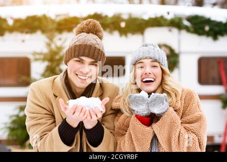 Winterstimmung. Fröhliches Junges Paar, Das Schnee In Den Händen Hält Und Die Kamera Anlächelt Stockfoto