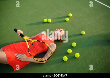 Müde weibliche Tennisspielerin liegt auf dem Platz Stockfoto