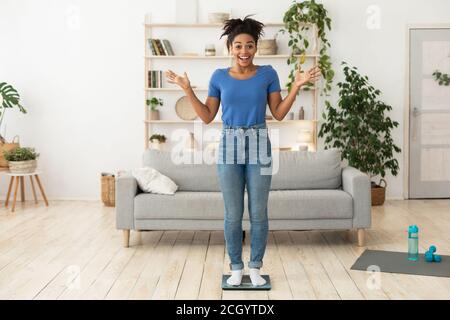 Aufgeregt Afroamerikanische Frau Nach Gewichtsverlust Stehen Auf Waage Im Innen Stockfoto