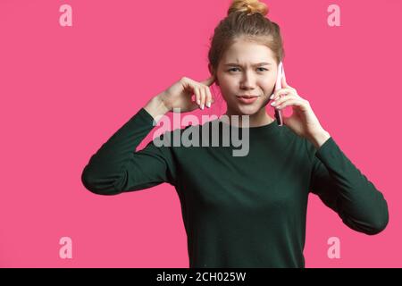 Die Frau war wegen der schlechten Telefonverbindung nicht zufrieden. Portrait einer unglücklichen, enttäuschten Schülerin mit Bun-Frisur, Stirnrunzeln, Abneigung gegen Whi Stockfoto