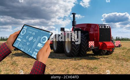 Ein Landwirt mit digitalen Tablet steuert eine autonome Traktor auf einem smart Farm Stockfoto