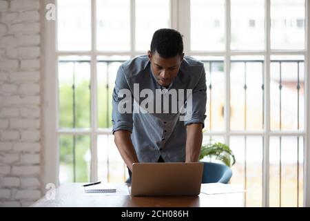 Afroamerikanischer männlicher Mitarbeiter beschäftigt mit Laptop Stockfoto