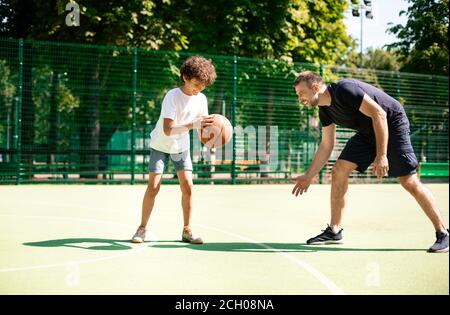 Reifer Trainer lehrt junge, wie man Basketball spielen Stockfoto