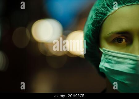 Nahsicht bei grünem Licht: Müder Arzt schaut Sie während der Nachtschicht an Stockfoto