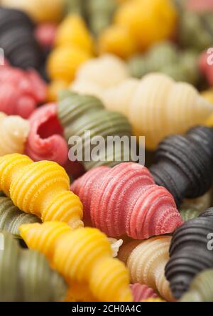 Frische rohe Conchiglioni tricolore Pasta als Textur Hintergrund. Makro Stockfoto