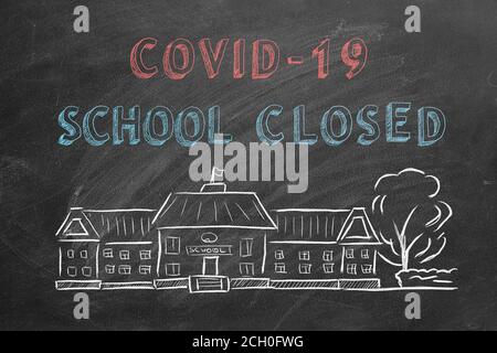Schulgebäude und Schriftzug COVID-19 Schule auf Tafel geschlossen. Handgezeichnete Skizze. Coronavirus-Konzept. Stockfoto