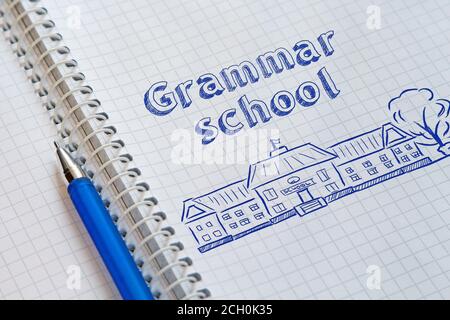 Notizbuch mit Spirale in einem Käfig und blauem Stift darauf. Auf der linken Seite gezeichnet die Schule und Beschriftung Gymnasium Stockfoto
