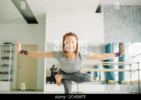 Nahaufnahme der charmante junge Frau, die in einem schwarzen Anzug das anspruchsvolle Yoga Übung Stehen auf einem Bein mit den Händen auseinander auf weißem Hintergrund isoliert Stockfoto