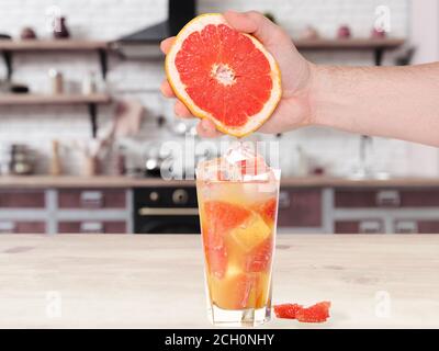 Männliche Hand hält Grapefruit auf Küche Hintergrund. Menschen lebendige Lebensstil, Konzept. Grapefruit-Set Stockfoto