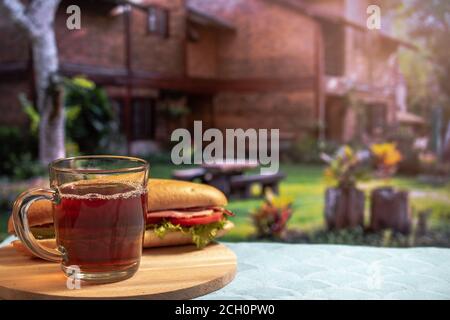 Eine Tasse schwarzen Kaffee oder Tee und Sandwich-Frühstück im Innenhof, Sommer, Lifestyle, horizontal Stockfoto