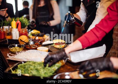 Beschnittene Ansicht der Köche Hände stehen in roh am Tisch und machen Hamburger und Burger. Stockfoto