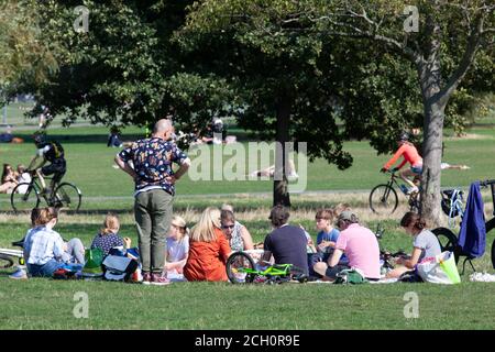 London, Großbritannien. 13. Sept 2020: Die Londoner nutzten das sonnige Wetter am Clapham Common am Tag bevor sich die sozialen Distanzierungsregeln ändern werden. Ab morgen wäre dieses Mehrfamilienpicknick illegal. Anna Watson/Alamy Live Nachrichten Stockfoto