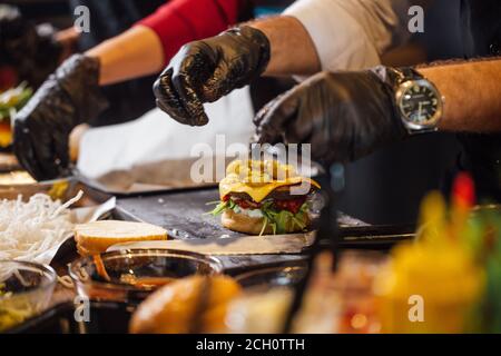 Beschnittene Ansicht der Köche Hände stehen in roh am Tisch und machen Hamburger und Burger. Küche und Gastronomie Stockfoto