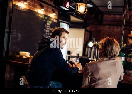 Rückansicht des jungen Paares genießen romantische Momente beim Sprechen in einem beliebten modernen Restaurant mit Loft-Interieur. Stockfoto