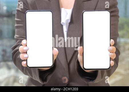 Mockup Handy. Geschäftsfrau in einem Anzug zeigt zwei Telefone. Stockfoto