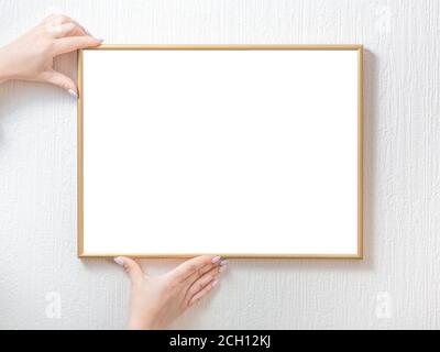 Frau Hände halten weißen leeren Fotorahmen hängen an der Wand. Bildrahmen-Modell Stockfoto