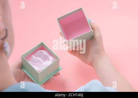 Junge Frau öffnet ein leeres Schmuckgeschenk, Frau mit einem offenen Schmuckschachtel. Rosa Hintergrund. Geschenk-Konzept. Stockfoto