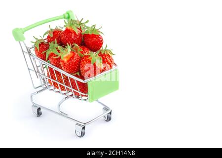 Lebensmittelkarre mit Erdbeeren auf weißem Hintergrund. Erdbeeren in einem kleinen Trolley von einem Supermarkt. Frische rote Erdbeeren. Erdbeere im Auto Stockfoto