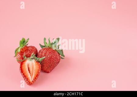 Einige Erdbeeren auf einem rosa Hintergrund. Frische rote Bio-Erdbeeren. Frischer Erdbeer-Smoothie, sommerliches gesundes Antioxidans. Copyspace. Stockfoto