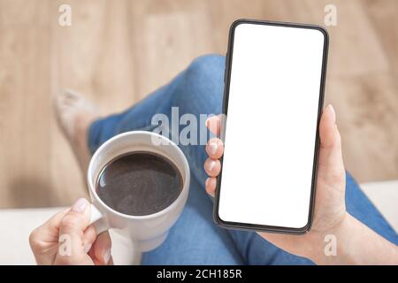 Mockup Bild der Frau hält schwarzes Handy mit leeren weißen Bildschirm im Café. Abgeschnittene Ansicht der Hände der Frau, die Smartphone mit leerem CO halten Stockfoto
