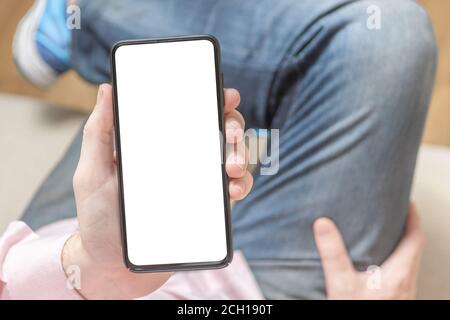 Mockup Bild der Hände des Mannes halten weißes Handy mit leerem Bildschirm. Handy mit Handgriff für Frauen und leerem Bildschirm. Mockup Telefon. Draufsicht. Stockfoto