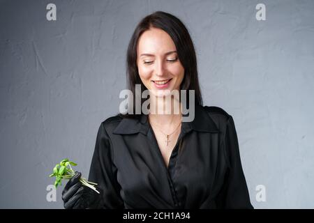 Foto einer lächelnden Frau, die grüne Sprossen in der Hand hält Stockfoto