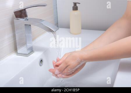 Hände Reinigen. Frauenhände Nahaufnahme unter fließendem Wasser im Badezimmer über dem Waschbecken. Hände Reinigen. Hygienekonzept Stockfoto