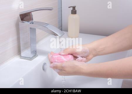 Frau benutzen Seife und waschen Hände unter dem Wasserhahn. Hände mit Seife unter dem Wasserhahn mit Wasser waschen. Hygiene Konzept Hand Detail. Hände Reinigen Stockfoto