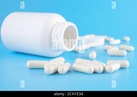 Medikamentenflasche und weiße Pillen verschüttet über blauen Hintergrund. Medikamente und verschreibungspflichtige Pillen Hintergrund. Pharmazeutische Arzneimittel. Medizin c Stockfoto