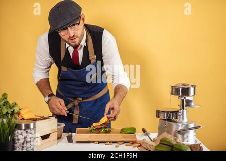 Koch Burger Vorbereitung auf die Masterclass im Studio auf gelbem Hintergrund Stockfoto