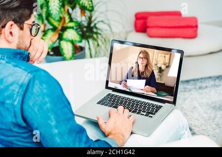Rückansicht des Geschäftsmannes, der hinter seinem Laptop sitzt und Diskussion und Online-Meeting in Videoanruf hat. Geschäftstreffen online. Stockfoto