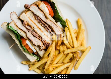 Gegrilltes Chicken Club Sandwich mit Pommes auf einem Teller Stockfoto