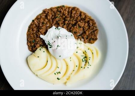 Hackfleisch und Kartoffeln mit pochierten Eiern auf einem Teller serviert Stockfoto