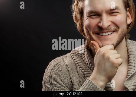 Nahaufnahme Foto von angenehmen jungen Mann mit der Hand auf dem Kinn. Copyspace Stockfoto