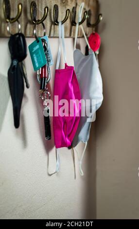 Seitenansicht eines Schlüsselregals mit Schlüsseln und Gesichtsmasken. Fokussiert auf die Pink Maske Stockfoto