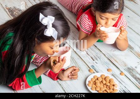 Kleinen Schwestern essen Cookies mit Milch am Weihnachtstag Stockfoto