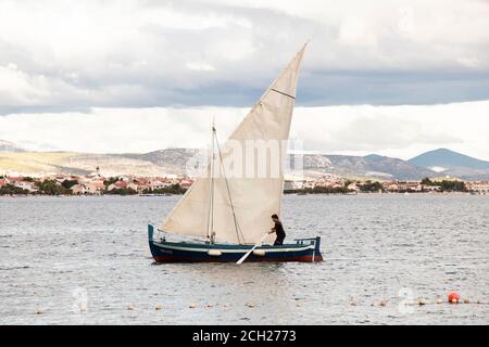 Vodice, Kroatien - 1. September 2020: Mann mit einem Paddel in einem Segelboot Stockfoto