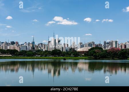 Ein allgemeiner Blick auf moderne Hochhäuser, die über den Bäumen emporragen und sich auf dem See im Parque Ibirapuera, einem großen Stadtpark in Sao Paulo, Brasilien, widerspiegeln Stockfoto