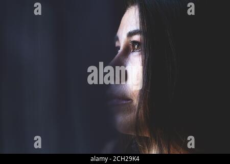 Junge attraktive Frau mit langen Haaren, Blick nach draußen, einsame Stimmung. Stockfoto