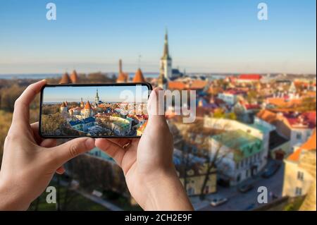 Touristen fotografieren das Stadtzentrum von Tallinn. Mann, der Telefon hält und Fotos von den Türmen Tallinns macht. Blick von oben auf Tallinn Stadtzentrum f Stockfoto