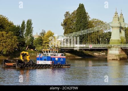 London, Großbritannien. - 13. September 2020: Ein Boot und ein Hinweis warnen den Flussverkehr, nicht unter die Hammersmith Bridge zu fahren. Die Brücke wurde im vergangenen Monat als so unsicher eingestuft, dass keine Fußgänger darauf dürfen und Boote nicht mehr darunter fahren können. Stockfoto